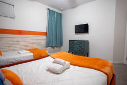 Rest in a bright Finding Nemo themed bedroom with two cozy beds, ocean-inspired mural, orange accents, soft carpet, and teal curtains. Playful sea details and cheerful colors create a fun space for kids during vacation.