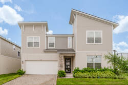 This stylish two-story vacation home boasts a bright exterior and large windows that fill the space with natural light. The lovely landscaping adds a splash of greenery, enhancing its inviting curb appeal for guests to enjoy.
