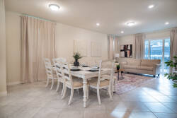 Bright and airy, this dining area features a charming white table set for six, complemented by soft beige curtains that frame the space. The cozy sofa invites relaxation, while stylish decor adds a welcoming touch to your stay.