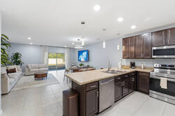 Cook with ease in a bright kitchen with dark cabinets, granite countertops, stainless steel appliances, pendant lights, and bar seating, creating a practical space for meals during your vacation.