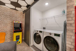 Experience a convenient laundry area with modern appliances hidden behind stylish sliding doors. Enjoy a vintage arcade game for a fun break while your clothes are washing, making chores feel more enjoyable.