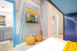 This cheerful bedroom, with its vibrant blue and yellow accents, creates a playful atmosphere. A fun Minions-themed wall adds character, and cozy poufs invite relaxation, making the space inviting and perfect for unwinding.