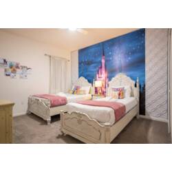 Rest in a dreamy princess-themed bedroom with two cozy beds, elegant white headboards, soft pink accents, and a magical castle mural under a starry sky. Playful pillows and gentle lighting create a sweet space for vacation.