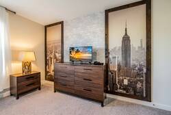 Experience comfort in this beautifully designed bedroom, featuring a plush carpet and a stunning cityscape wall. The warm bedside lamp enhances the rich wood furniture, creating a cozy atmosphere perfect for relaxation.