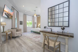 This stylish room offers a cozy seating area with a comfy armchair and a sleek desk, ideal for planning your adventures. Large windows bring in natural light, highlighting the warm wood tones and soft textiles for a welcoming.