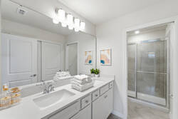 Refresh in a bright bathroom with a white vanity, large mirror, soft lighting, fresh towels, glass shower, neutral tile, and simple modern decor for vacation comfort.