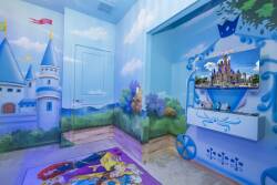Enter a whimsical space with vibrant blue walls and enchanting castle murals, perfect for young dreamers. A cozy rug adds warmth, while the inviting TV area sets the stage for fun movie nights.