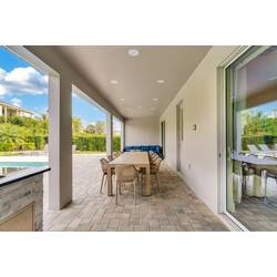 Enjoy a covered patio with outdoor dining, cozy lounge seating, pool views, and direct access to the backyard, creating a comfortable space for meals and relaxing in the Florida sun.