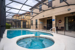 Step outside to find a private oasis with a sparkling pool and inviting hot tub, all screened for your comfort and privacy. The cozy seating area nearby invites you to relax and soak in the serene atmosphere.