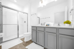 This bright bathroom boasts sleek gray cabinetry and modern fixtures, enhancing its contemporary vibe. Enjoy the spacious shower and clean lines, all complemented by soft white towels for a refreshing atmosphere during your stay.