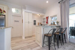 This stylish kitchen boasts sleek cabinetry and a welcoming island with modern bar stools, ideal for casual dining. Natural light brightens the space, creating an airy atmosphere for you to enjoy your culinary creations.