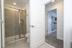 Experience a contemporary bathroom with sleek glass shower doors and elegant gray tile, adding sophistication to your stay. The clean lines and bright lighting create a refreshing atmosphere for a truly rejuvenating experience.