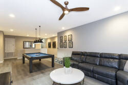 Welcome to a lively gathering space featuring a sleek leather sectional for relaxation and a vibrant pool table under stylish pendant lighting, complemented by textured wall art that creates an inviting atmosphere for socializing.
