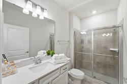 Refresh in a bright bathroom with a large mirror, white vanity, soft lighting, fresh towels, glass shower, neutral tile, and clean modern details for vacation comfort.