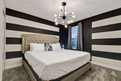 Enjoy restful nights in this stylish bedroom with plush bedding on a chic upholstered bed. The bold black and white striped walls create a striking backdrop, enhanced by a modern light fixture that adds flair to your stay.