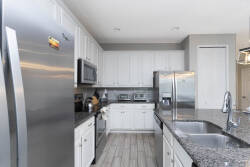 Experience a beautifully designed kitchen featuring stainless steel appliances, elegant white cabinetry, and stunning granite countertops.