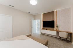 Experience a bright and airy bedroom with a plush bed and sleek wall-mounted TV, where calming pastel tones create a serene atmosphere. A stylish desk nook awaits for quiet moments or planning your adventures.