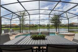 Step outside to your private oasis, where a shaded patio invites you to relax around the sleek dining table. Enjoy tranquil water views as you unwind by the sparkling pool, surrounded by lush greenery and open skies.
