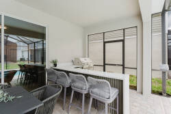 Experience our stylish outdoor dining area featuring modern gray bar stools and a sleek countertop, perfect for casual meals or evening gatherings, all while enjoying stunning views through the floor-to-ceiling windows.
