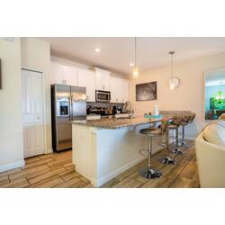 Unwind at the sleek granite island in this modern kitchen, where stainless steel appliances gleam under soft pendant lights. Cozy bar stools invite casual chats or morning coffee, creating a warm, welcoming space for your stay.