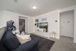 Experience a cozy living area with a plush navy sofa and soft pillows, paired with a sleek white media console. Bright walls and warm lighting make it the perfect space to relax after a day of adventure.