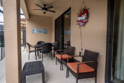 Step onto this spacious patio, where stylish wicker chairs with bright orange cushions invite you to relax. Enjoy a refreshing breeze from the ceiling fan as warm earth tones create a cozy atmosphere for your comfort.
