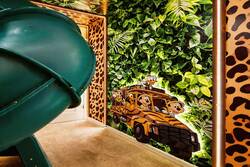 Enjoy a playful safari themed bunk room with cozy bunk beds, a fun indoor slide, jungle ceiling details, warm lighting, and soft carpet, creating an exciting space for kids during vacation.
