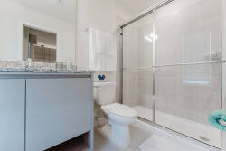 Experience a bright, modern bathroom with sleek glass shower doors and polished granite countertops for a touch of sophistication. The light color palette creates an airy, refreshing atmosphere perfect for relaxation.