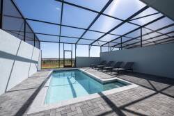 Step into your private oasis featuring a sparkling pool surrounded by sleek paver stones and comfortable loungers, all under a spacious screened enclosure. Enjoy sunlit afternoons and relaxing evenings in this tranquil setting.