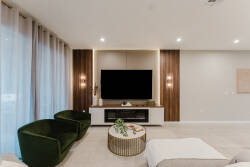 Relax in the inviting living area with rich green velvet chairs and a sleek coffee table. Large windows with soft curtains let in natural light, creating a warm and airy ambiance perfect for unwinding.