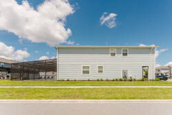 This charming home features soft blue siding that beautifully matches the sky, while the lush green lawn invites you outside. Large windows fill the space with natural light, creating a warm and welcoming atmosphere.