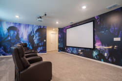 Experience your own private cinema with plush leather recliners and a large screen, perfect for movie nights. The vibrant mural adds a playful touch, creating an inviting atmosphere for relaxation and entertainment.