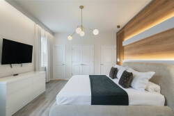 Relax in a beautifully designed bedroom with stylish lighting, a plush bed with rich textures, and a soothing color palette. The modern furnishings offer a comfortable atmosphere ideal for unwinding after a long day.