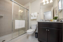 This modern bathroom features a sleek glass shower, complemented by elegant lighting and a rich wooden vanity. Enjoy the comfort of plush towels and a tasteful decor that creates a refreshing atmosphere for your stay.