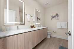 This bright and airy bathroom boasts a sleek double vanity in light wood and modern lighted mirrors, creating a spacious atmosphere. Soft towels are neatly arranged, inviting you to relax in style after a long day.