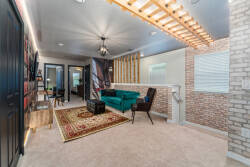 Experience a stylish living area with a vibrant teal sofa that pairs beautifully with exposed brick and warm wooden accents. Soft lighting sets a cozy mood, inviting you to relax and appreciate the artistic decor all around.