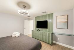 Experience a stylish bedroom with a cozy king-sized bed, soft linens, and a chic accent wall framing a wall-mounted TV. The minimalist decor and warm lighting create a relaxing atmosphere for your stay.