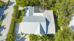 Experience the unique architecture of this home with its striking metal roof and inviting layout, nestled in lush greenery. The screened-in area is ideal for outdoor relaxation, letting you savor the warm breezes.