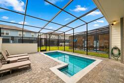 Enjoy a private screened pool area with lounge chairs, covered patio dining, ceiling fan, and open sky views, perfect for swimming, relaxing, and family meals during vacation.