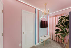 Immerse yourself in a vibrant oasis with cheerful pink walls and soft lighting, where a chic chandelier adds sophistication and lush greenery invites you to relax and unwind in this delightful atmosphere.
