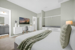 Step into a tranquil bedroom adorned with soft green walls and a plush white bed, complemented by a cozy throw blanket. The room features a sleek desk area and a stylish TV console, enhancing both comfort and functionality.