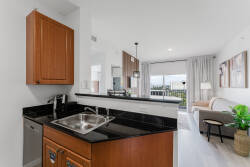 Experience a stylish kitchen with beautiful wooden cabinetry and sleek black countertops, bathed in natural light. The open layout seamlessly blends cooking and relaxation, ideal for your culinary adventures.