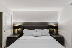 Experience a cozy atmosphere in this stylish bedroom featuring a contemporary dark wood bed frame and sleek nightstands, enhanced by modern lamps. Enjoy soft white bedding and gentle accent lighting for restful nights.