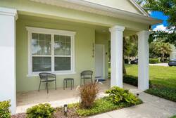 Step outside to a charming porch where two stylish metal chairs invite you to relax. The lush greenery and well-kept landscaping frame the entrance, creating a welcoming vibe that sets the tone for your stay.