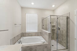 Unwind in a bright bathroom with a soaking tub, glass shower, neutral tile, soft natural light, and clean modern finishes, creating a relaxing space after a day out.