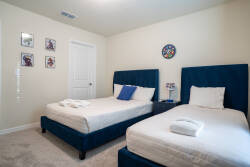 Bright and airy, this cozy room features two plush twin beds with stylish blue upholstered headboards, offering comfort for a restful night. Whimsical artwork adorns the walls, adding a playful touch to your stay.
