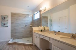 Begin your day in this spacious bathroom with a bright walk-in shower, elegant tile work, and plenty of natural light. The dual sinks and stylish fixtures enhance the serene, soothing ambiance for a refreshing experience.
