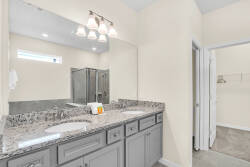Enjoy our spacious bathroom with a beautiful double vanity and sleek granite countertops, paired with modern lighting for a fresh, neutral vibe. The stylish glass shower brings a touch of luxury to your refreshing experience.