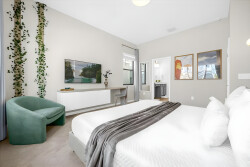 Relax in this stylish bedroom with a plush bed, soft linens, and a calming color palette. A unique green chair adds vibrancy, while natural light fills the room, creating a refreshing and inviting atmosphere for your stay.