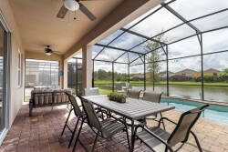 Enjoy the charming covered patio with a spacious dining table and cozy seating, ideal for outdoor meals. Relax with serene water views through the screen enclosure, complemented by inviting rustic brick flooring.